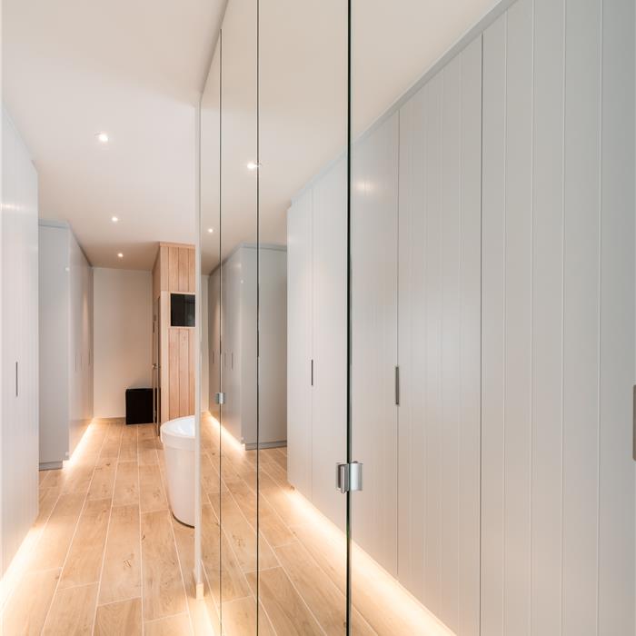 Spiegelwand met reflectie van de kamerhoge badkamerkasten op maat