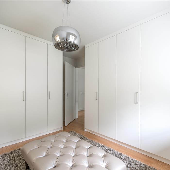 Hoge witte maatkasten in dressing met deuren tot tegen het schuine plafond