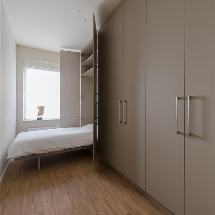 Maatkast met geopend geïntegreerd uitklapbed in logeerkamer in Antwerpen