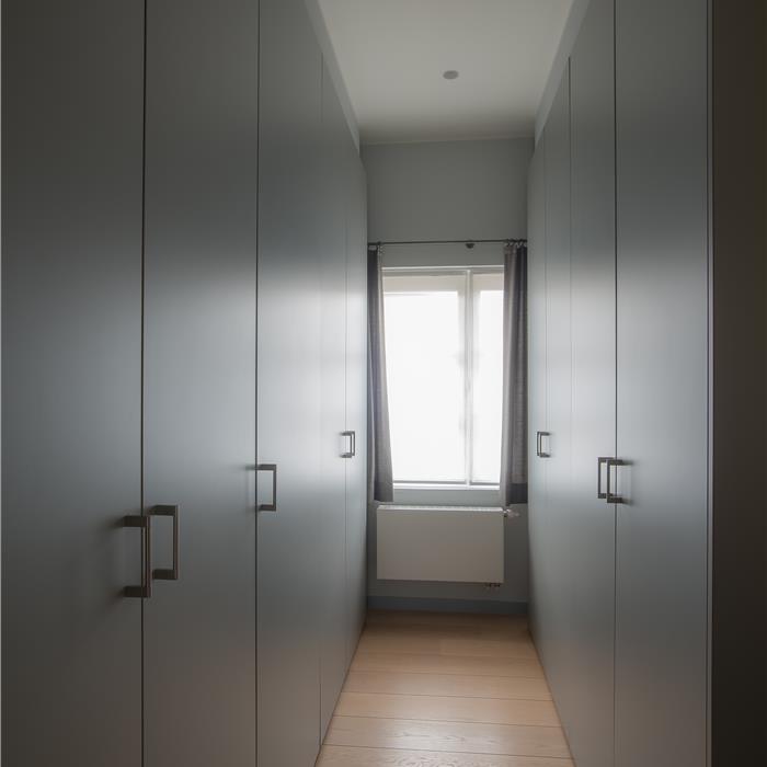 Hoge maatkasten van vloer tot plafond in een grijze inloopdressing