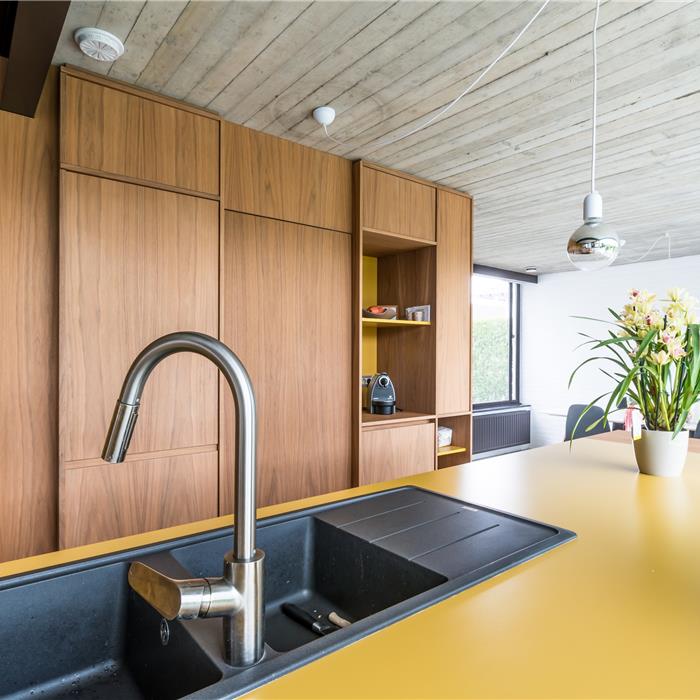 keuken op maat in Vorselaar, met maatkasten in notelaar, close-up van het eiland met keukenwerkblad en spoelbak, zij-aanzicht