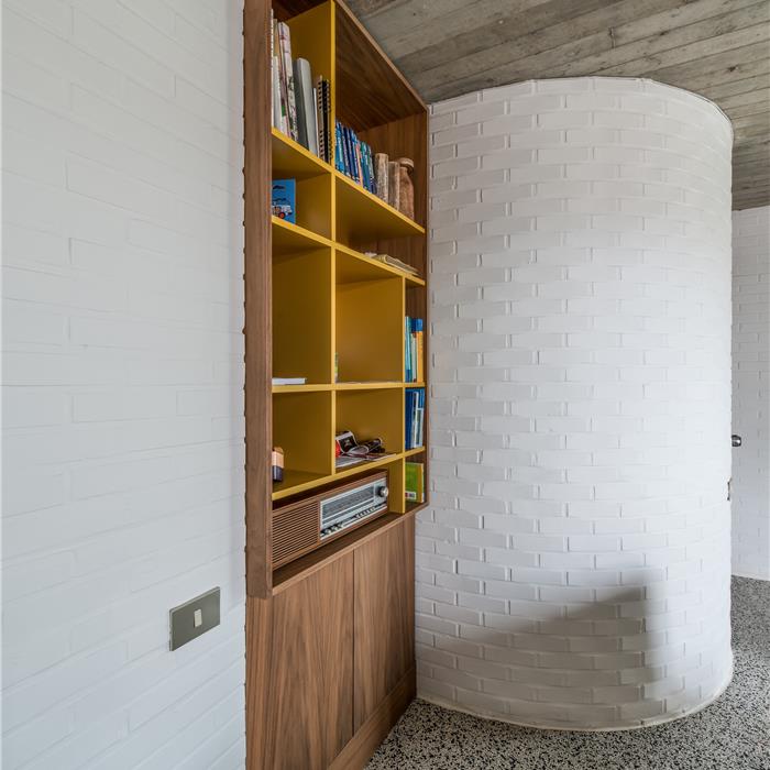 Boekenkast met houtfineer en gele laminaat als onderdeel van dit maatwerk interieur in Vorselaar.