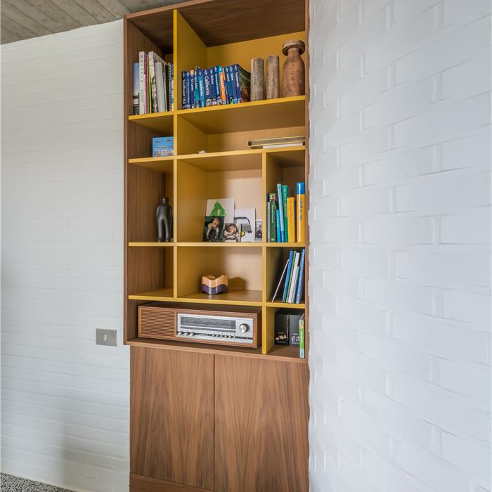 Boekenkast in houtfineer en gele laminaat als onderdeel van dit interieur op maat in Vorselaar.