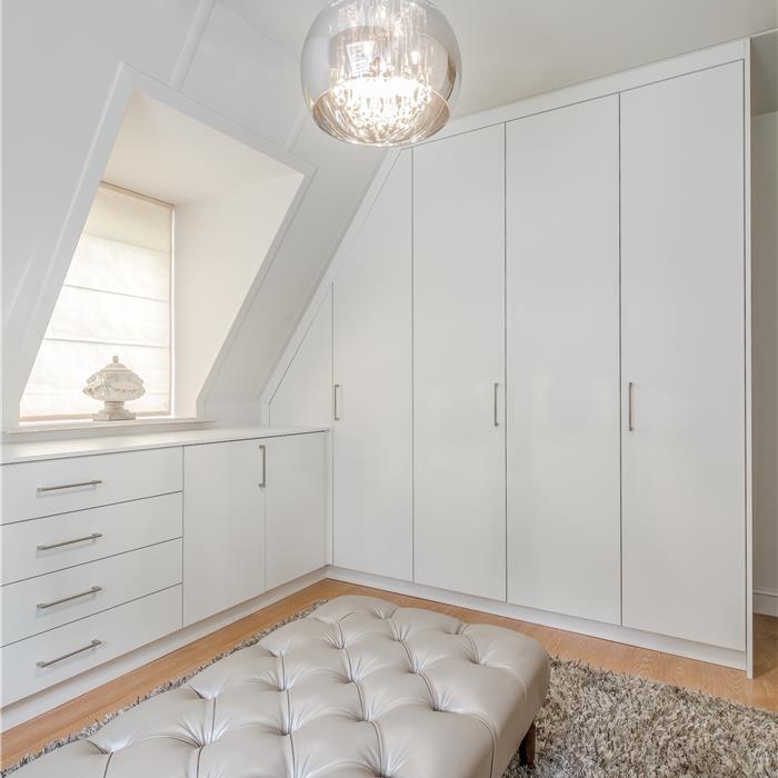 Witte maatwerk dressing met laden en hoge kast naast het dakraam