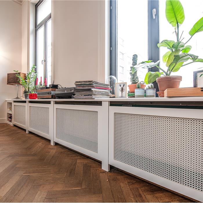 Witte radiatorombouw op maat onder de ramen van de leefruimte in Antwerpen