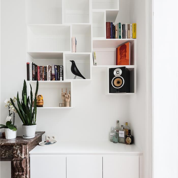 Witte wandkast op maat met asymmetrische open vakken voor boeken en decoratie