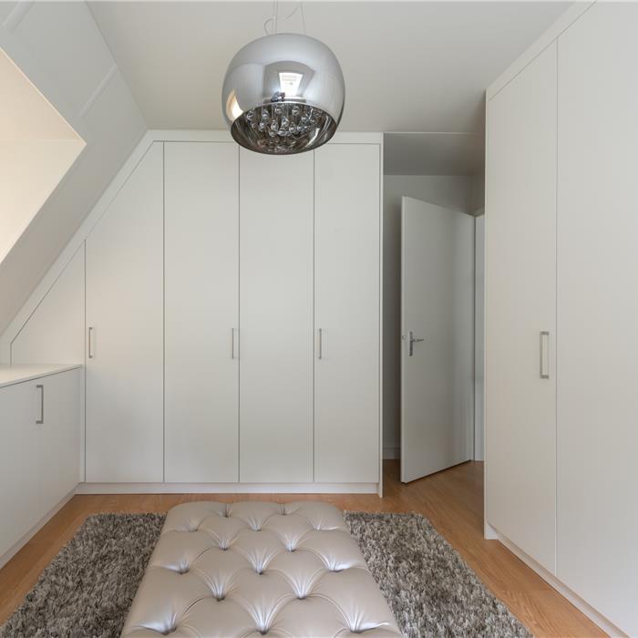 Witte dressing op maat met hoge en lage kasten onder schuin dak