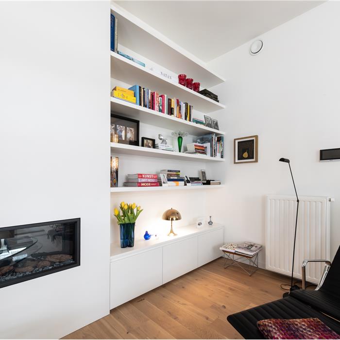 Wittemaatkast met open boekenplanken naast ingebouwde haard in woonkamer