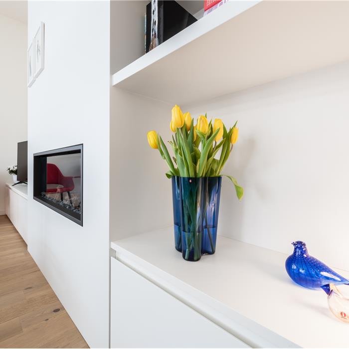 Detail van witte maatkast met open wandplanken in woonkamer