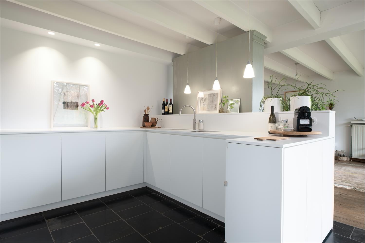 Keukenkasten en eiland als onderdeel van de minimalistische witte keuken met Silestone werkblad in Kalmthout