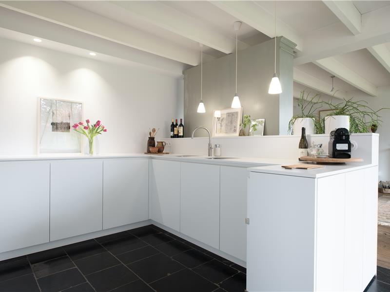 Keukenkasten en eiland als onderdeel van de minimalistische witte keuken met Silestone werkblad in Kalmthout
