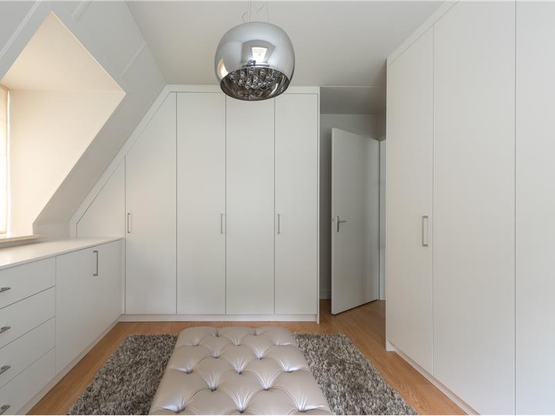 Witte dressing op maat met hoge en lage kasten onder schuin dak